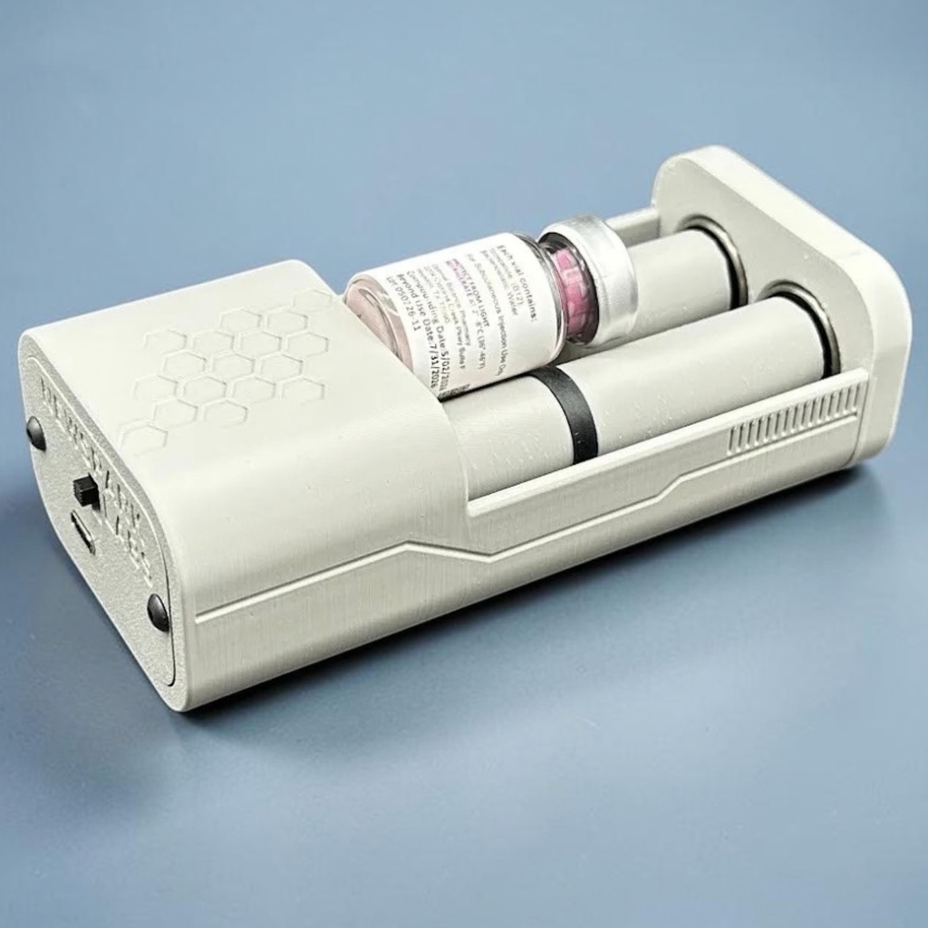An open, gray, motorized vial roller holder with one vial nestled between two rollers, shown on a blue-gray gradient background. there is a decorative honeycomb on the top and some decorative ridges on the side.
