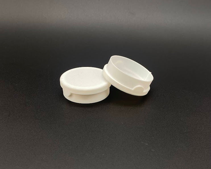 Two white plastic lids on a black background